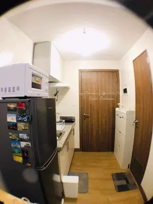 a kitchen with a refrigerator and a wooden door at Sky Suites at Spring Residences Condotel near NAIA and SM Bicutan Mall in Manila