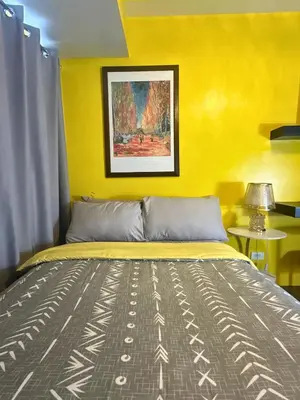a bedroom with a bed with a yellow wall at Air Residences- Netflix with City View in Manila