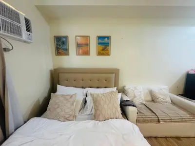 a bedroom with a bed with pillows and a fan at Berkeley Breeze Staycation in Silang