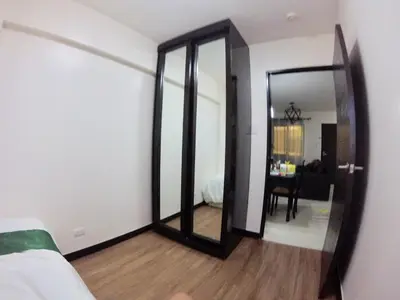 a room with a mirror and a bed and a table at Arista Place 2 bedroom Condo near airport in Manila