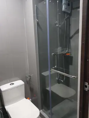 a bathroom with a toilet and a glass shower at Fully-furnished 1-br unit in Manila