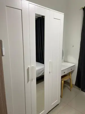 a white cabinet with a mirror next to a bed at The Ren Suite Facing Amenities in Manila