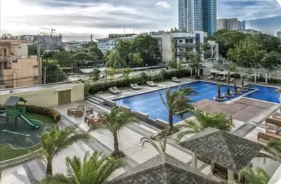 a large swimming pool with palm trees in a city at LaVerti 1BR Affordable staycation groups family in Manila