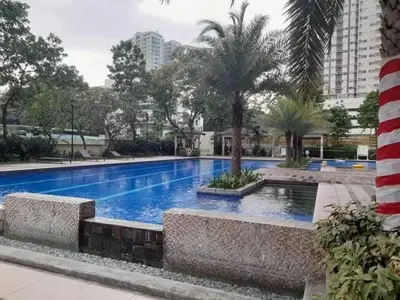 a large blue swimming pool with palm trees and buildings at LaVerti 1BR Affordable staycation groups family in Manila