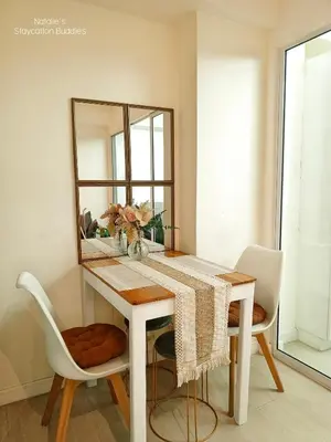 a dining room table with a mirror and white chairs at Natalie Staycation Buddies in Manila