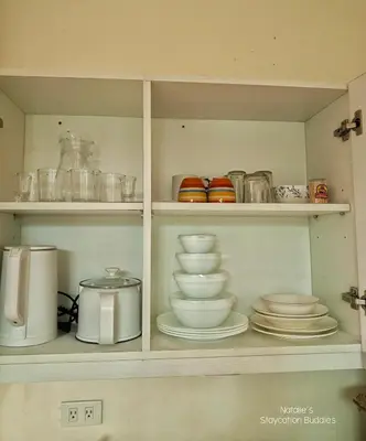 a cabinet filled with plates and bowls and appliances at Natalie Staycation Buddies in Manila