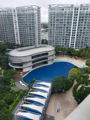 a large building with a swimming pool in front of it at Natalie Staycation Buddies in Manila