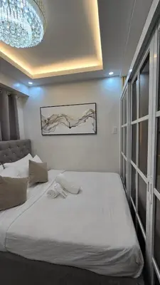 a bedroom with a large white bed and a chandelier at Sevillano's City Escape at Shore 1 Near MOA in Manila