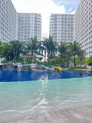 a large swimming pool with palm trees and buildings at Sevillano's City Escape at Shore 1 Near MOA in Manila