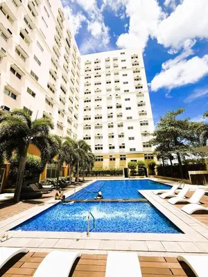 a swimming pool in front of a large building at JFam Suites, C4-10U Studio, Up To 4 Pax in Biñan