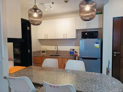 a kitchen with a table with chairs and a refrigerator at Modern Spacious 2BR 68 sqm Condo in Manhattan Heights Pool View in Manila