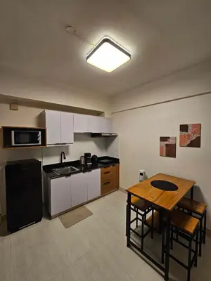 a kitchen with a table and a kitchen with white cabinets at Affordable Condo Suite with WIFI in McKinley BGC in Manila