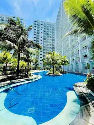 a large swimming pool with palm trees and a building at DS Staycation in Manila