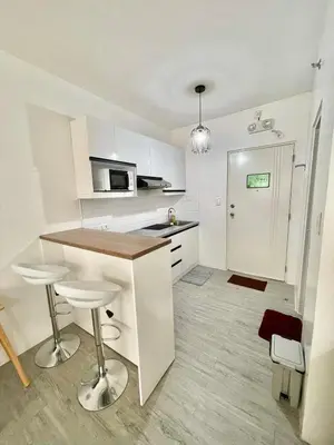 a kitchen with white cabinets and a counter with stools at Nuvali - Free use of Massage Chair-Pool Access-Hot Shower in Calamba