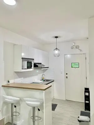 a kitchen with white cabinets and a counter with stools at Nuvali - Free use of Massage Chair-Pool Access-Hot Shower in Calamba