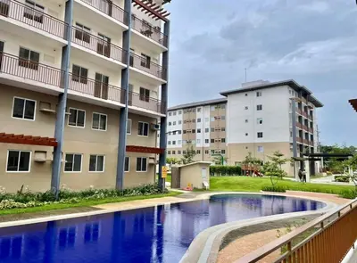 an apartment complex with a swimming pool in front of a building at Nuvali - Free use of Massage Chair-Pool Access-Hot Shower in Calamba