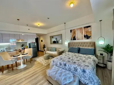 a bedroom with a bed and a living room at Modern Condo at The Venice Luxury Mckinley Hill in Manila