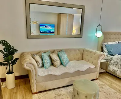 a living room with a couch and a mirror at Modern Condo at The Venice Luxury Mckinley Hill in Manila