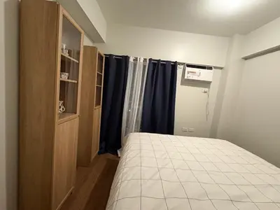 a bedroom with a bed and a window with blue curtains at Modern 2BR Condo with Balcony in Central Manila in Manila