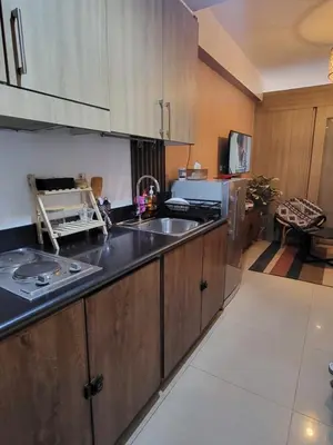 a kitchen with wooden cabinets and a sink at Balay Maria at Shore in Manila