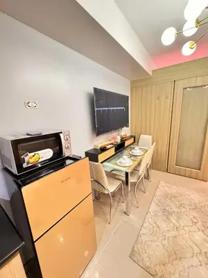a kitchen and dining room with a table and a television at Shore Staycation in Manila