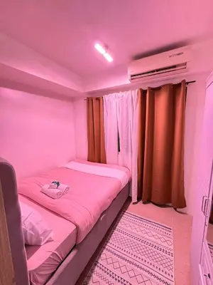 a small room with a bed with pink lighting at Shore Staycation in Manila