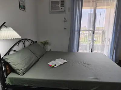 a bedroom with a bed with a lamp and a window at Windsong Suite Unli Netflix Disney Roofdeck View in Manila