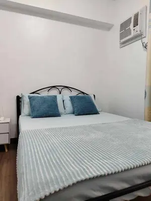 a bed with blue pillows in a white bedroom at Windsong Suite Unli Netflix Disney Roofdeck View in Manila