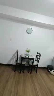 a dining room table with two chairs and a clock on the wall at Windsong Suite Unli Netflix Disney Roofdeck View in Manila