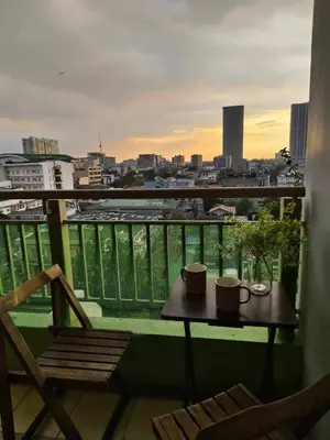 a balcony with a table and chairs and a view of a city at Windsong Suite Unli Netflix Disney Roofdeck View in Manila