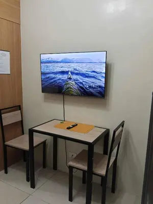 a table with two chairs and a tv on a wall at Serene Pasay Getaway - Entire Apartment for Rent in Manila