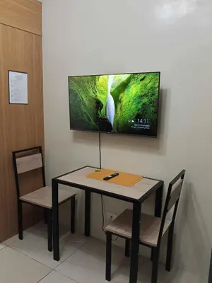 a table and chairs with a television on a wall at Serene Pasay Getaway - Entire Apartment for Rent in Manila
