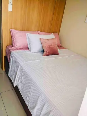 a bed with pink and white pillows on it at Relax in Pasay City at Shell Residences - Your Home Away from Home in Manila