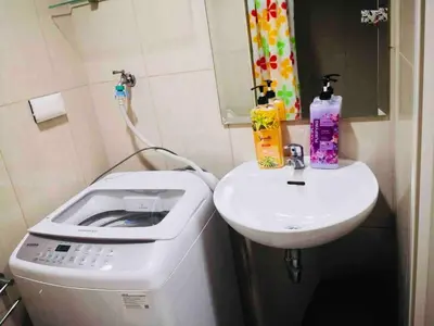 a small bathroom with a sink and a washing machine at Relax in Pasay City at Shell Residences - Your Home Away from Home in Manila