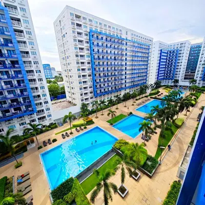 an overhead view of two pools in a city with tall buildings at Sea Residences Yanah Staycation in Manila