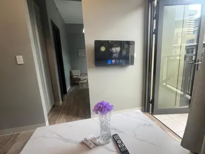 a vase with purple flowers on a table with a tv at Gentry Manor Seaview Family Suite balcony View WiFi Netflix 17S in Manila
