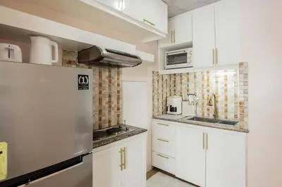 a kitchen with white cabinets and a refrigerator at Devi Suite 2BR BGC Taguig in Manila