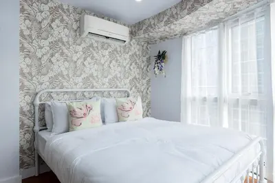 a bedroom with a white bed with floral wallpaper at Devi Suite 2BR BGC Taguig in Manila