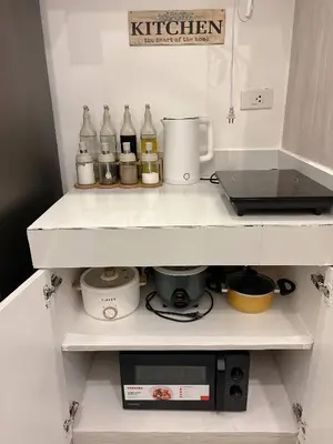 a kitchen with a shelf with bottles and a microwave at Cozy Loft Condo in Tanza with Arcade in Tanza