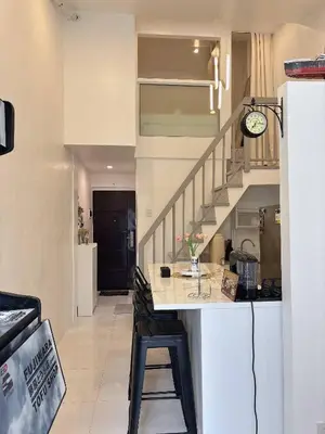 a kitchen and living room with a counter and a staircase at Cozy Loft Condo in Tanza with Arcade in Tanza