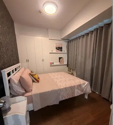 a small bedroom with a bed and a window at Forbeswood Parklane Condominium in Manila