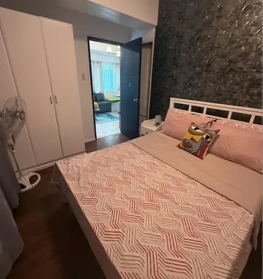 a bedroom with a large bed with two pillows on it at Forbeswood Parklane Condominium in Manila