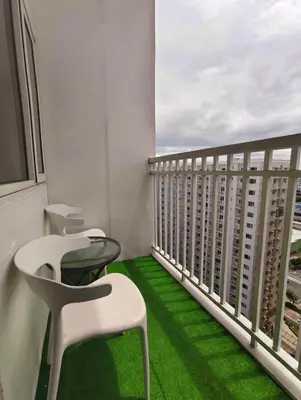 a balcony with white chairs and a green floor at The C Place Mla in Manila