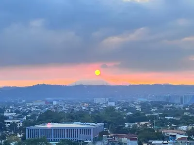 a view of a city with the sun in the sky at Cozy Nook in the City in Manila