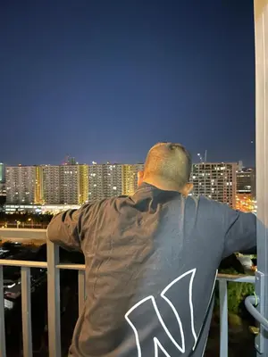 a man sitting on a balcony looking out at the city at Teychi's Staycation at Shore2 MOA Pasay in Manila