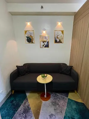 a living room with a black couch and a table at Teychi's Staycation at Shore2 MOA Pasay in Manila
