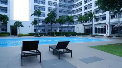 two chairs sitting next to a swimming pool in a building at Zen Staycation with City and Sunset View near Airport and Mckinley in Manila