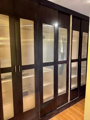 a dark wood cabinet with glass doors at WestParc Cedar Cozy Apartment in the Heart of Alabang in Manila