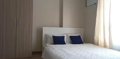 a bedroom with a bed with blue pillows and a window at The Verdin Brand-New Unit with Pool, Gym, & High-Speed Wi-fi in General Trias