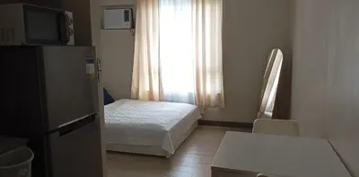 a small bedroom with a bed and a window at The Verdin Brand-New Unit with Pool, Gym, & High-Speed Wi-fi in General Trias